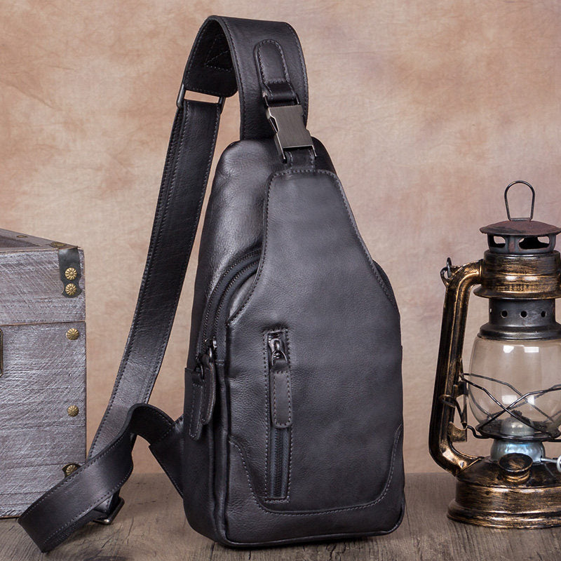 Black leather sling bag on a wooden surface with a rustic background