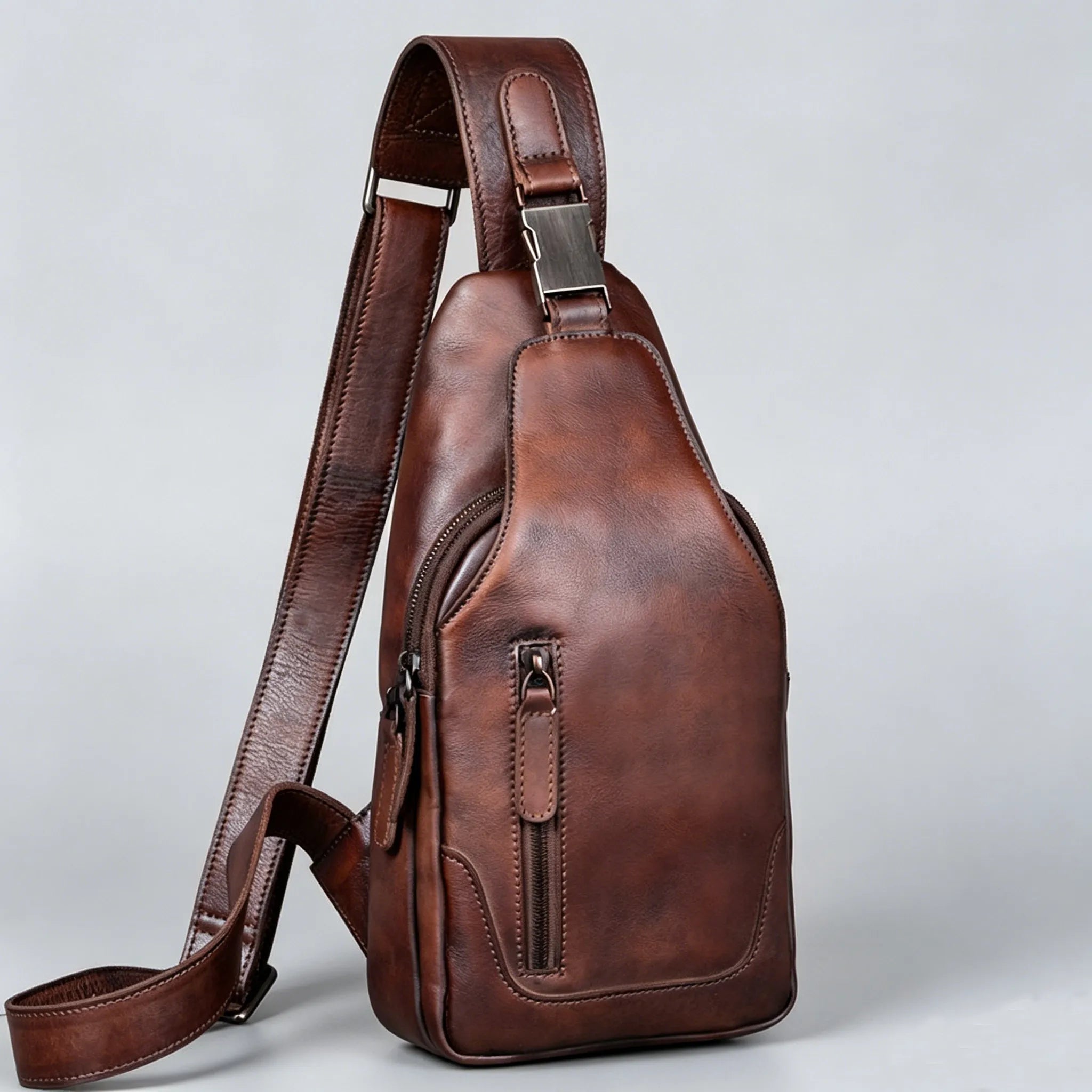 Brown leather sling bag on a light gray background