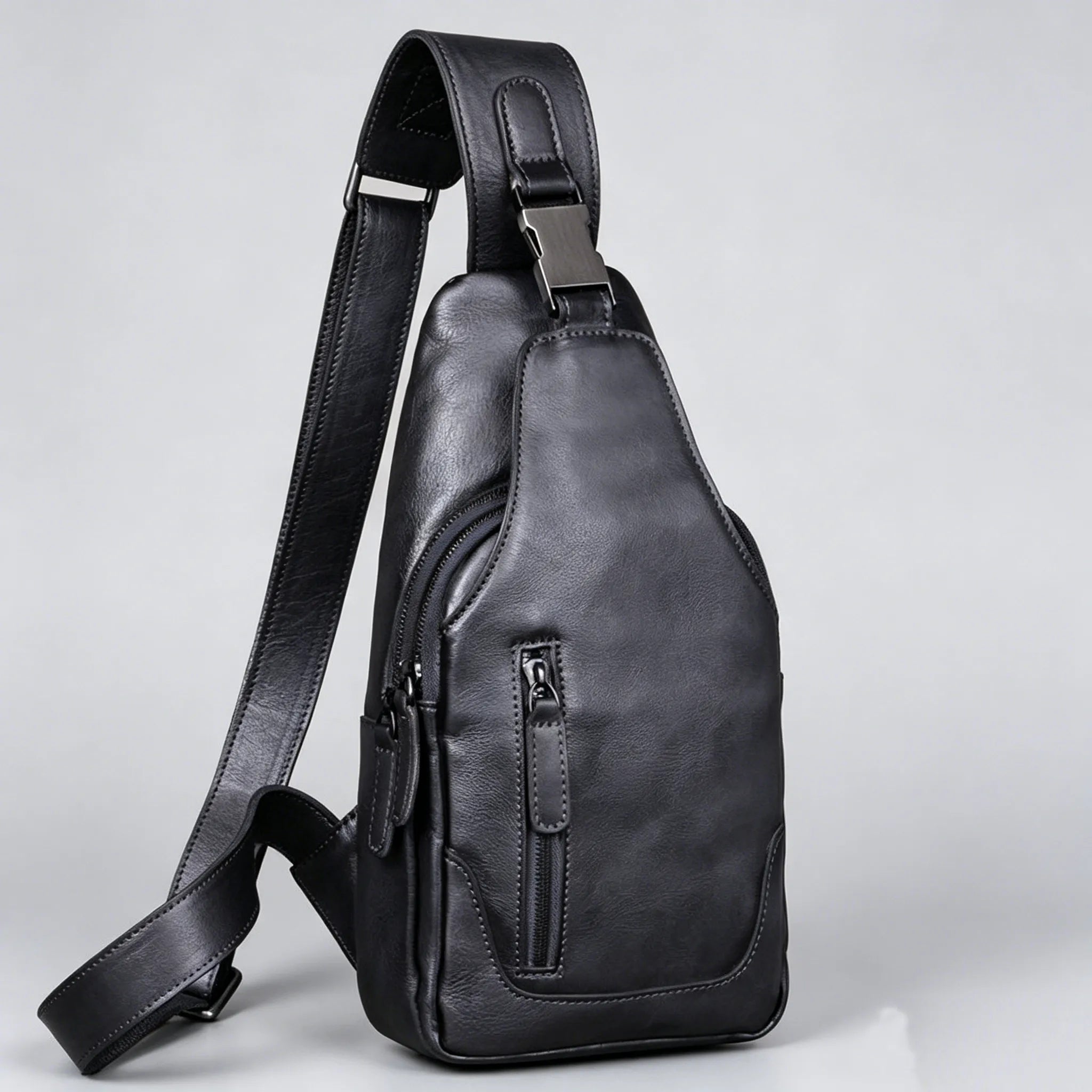 Black leather sling bag on a light gray background