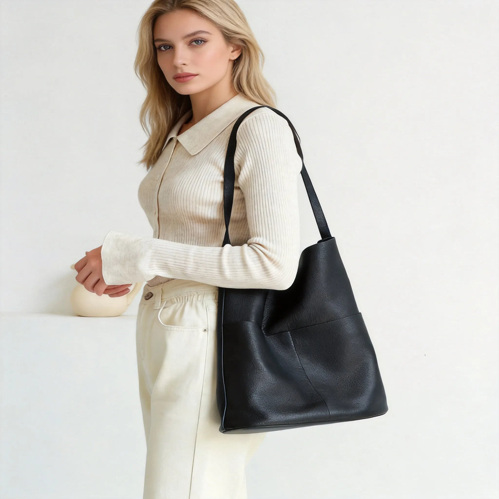 Woman holding a black leather handbag against a white background