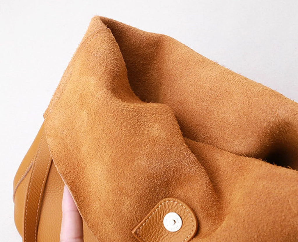 Close-up of a brown leather bag with a button on a light gray background