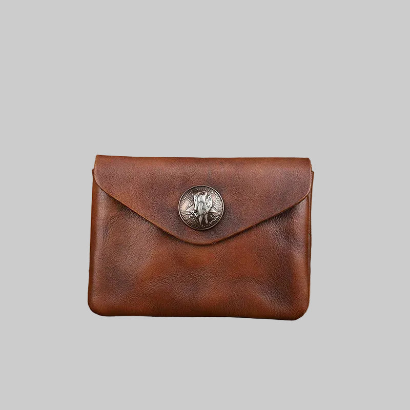 Brown leather wallet with a metal emblem on a wooden surface
