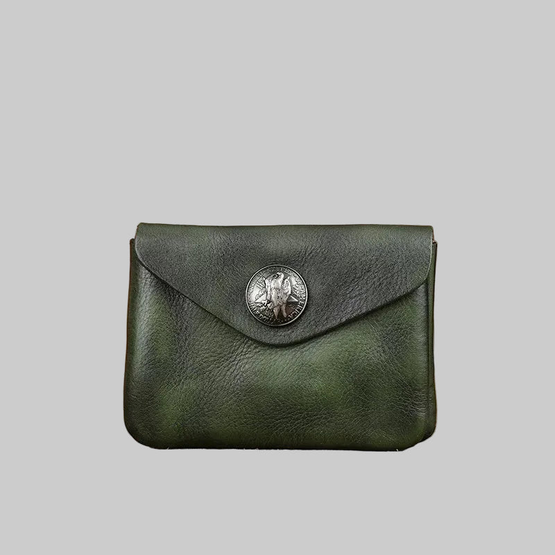 Green leather wallet with a metal emblem on a wooden surface