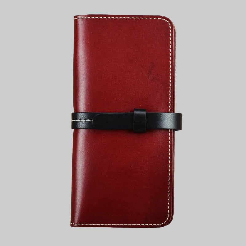 Red leather wallet with a black strap on a brown background