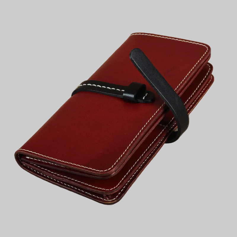 Red leather wallet with a black strap on a beige background