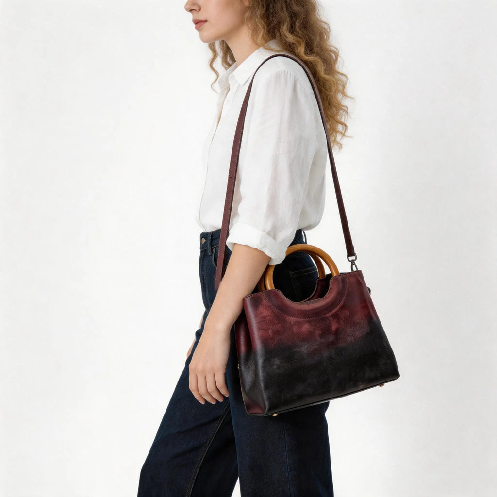 Woman holding a dark brown leather handbag with wooden handle on a white background