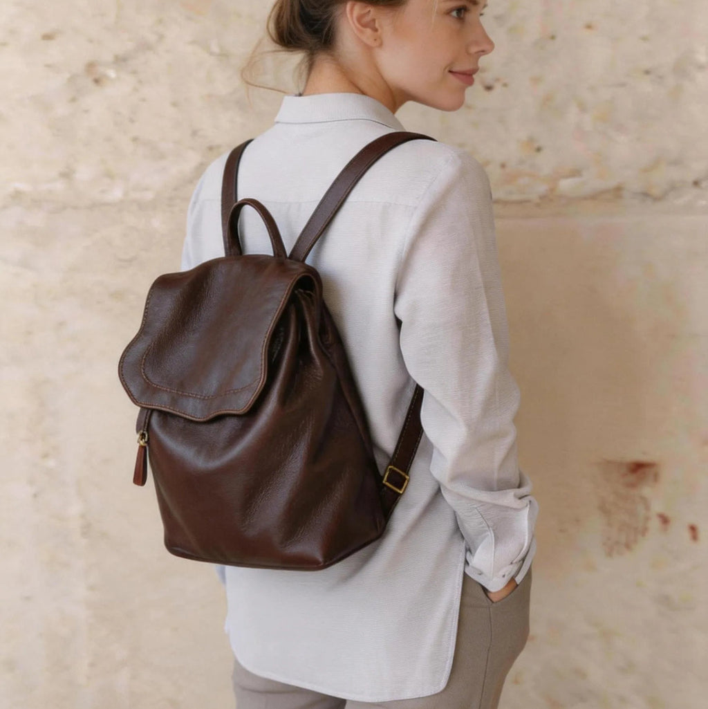 Woman wearing a brown backpack against a textured beige wall