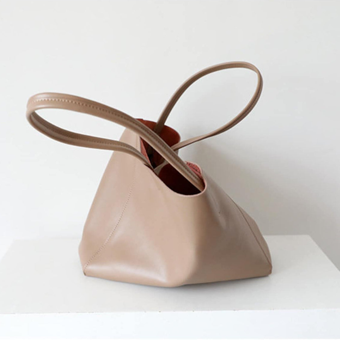 Beige handbag with brown handles on a white surface