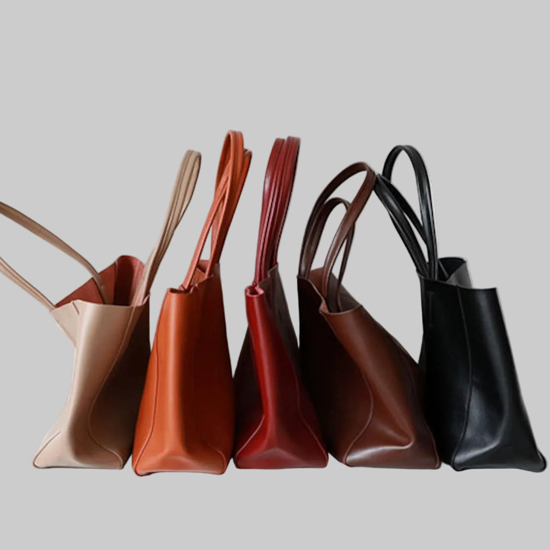 Five leather handbags in different colors arranged in a row on a light gray background.