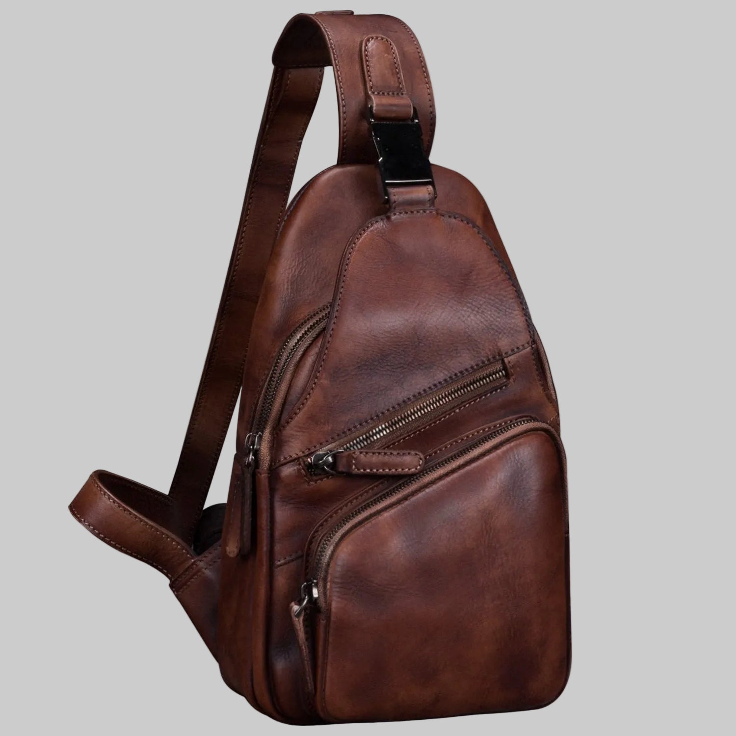 Brown leather sling bag on a light gray background