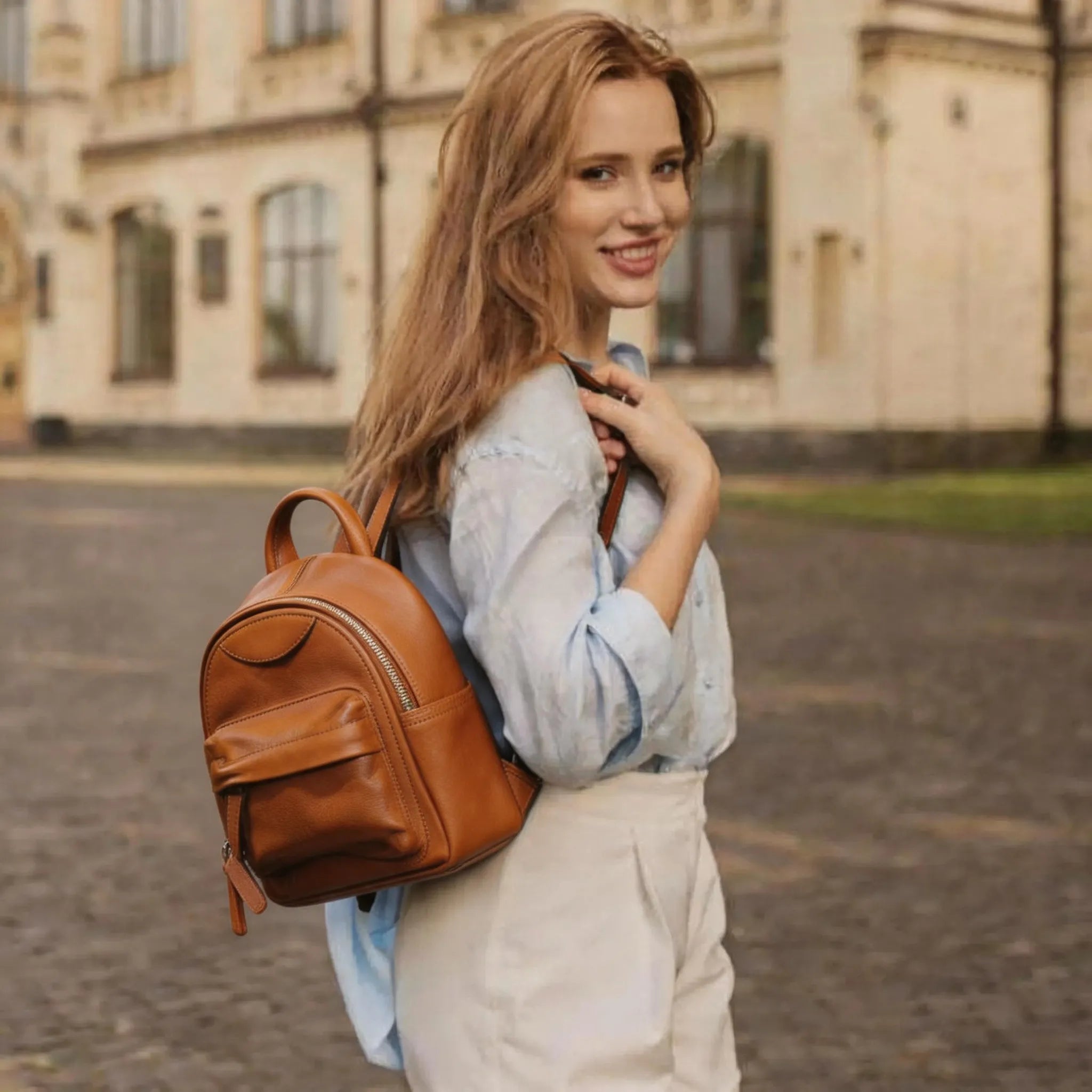 Woman with a brown backpack standing outdoors in front of a building
