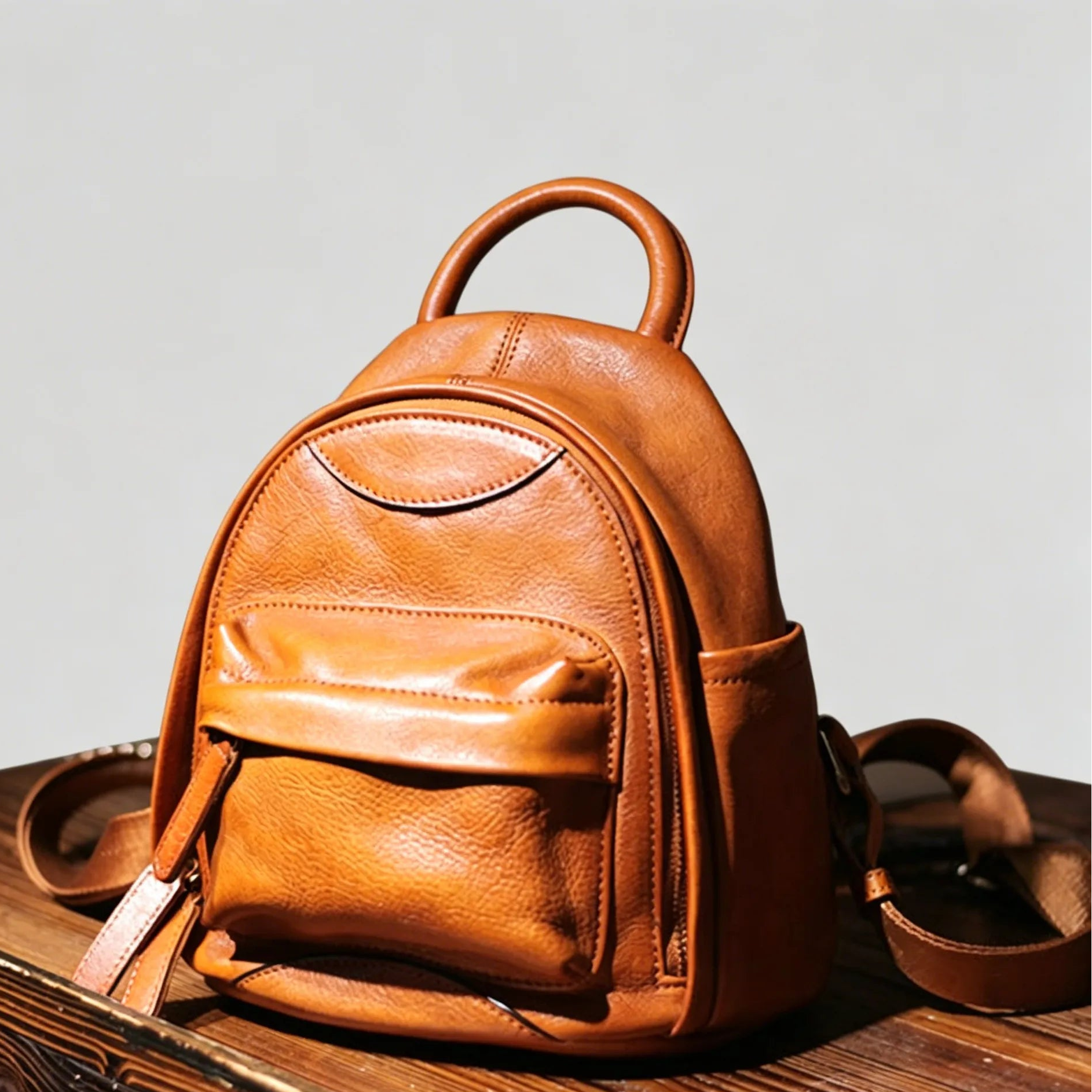 Brown leather backpack on a wooden surface with a light gray background