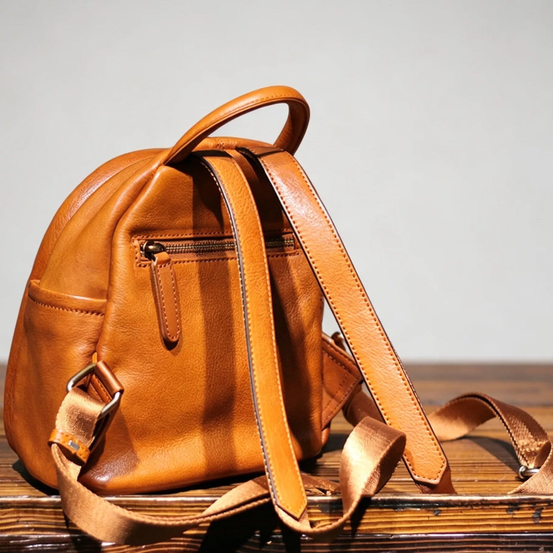 Brown leather backpack on a wooden surface with a neutral background