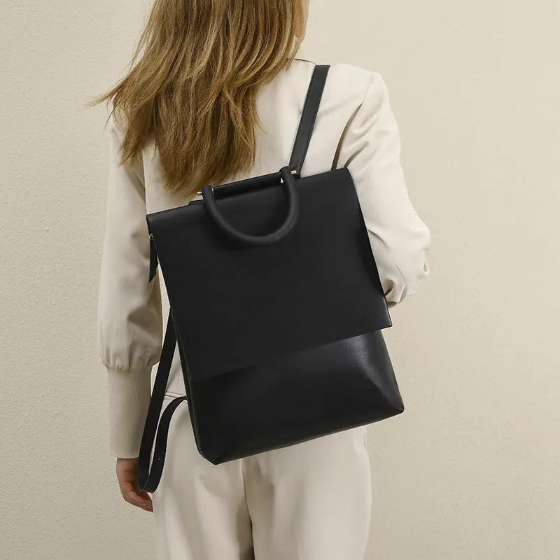 Person wearing a black backpack against a plain background