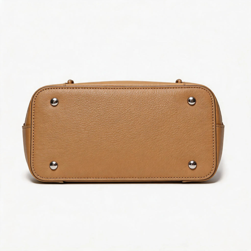 Tan leather handbag with silver studs on a white background