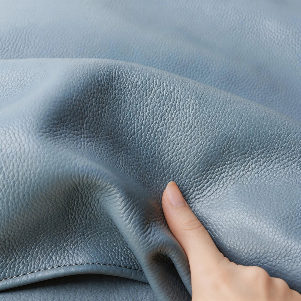 Close-up of blue leather fabric with a hand touching it