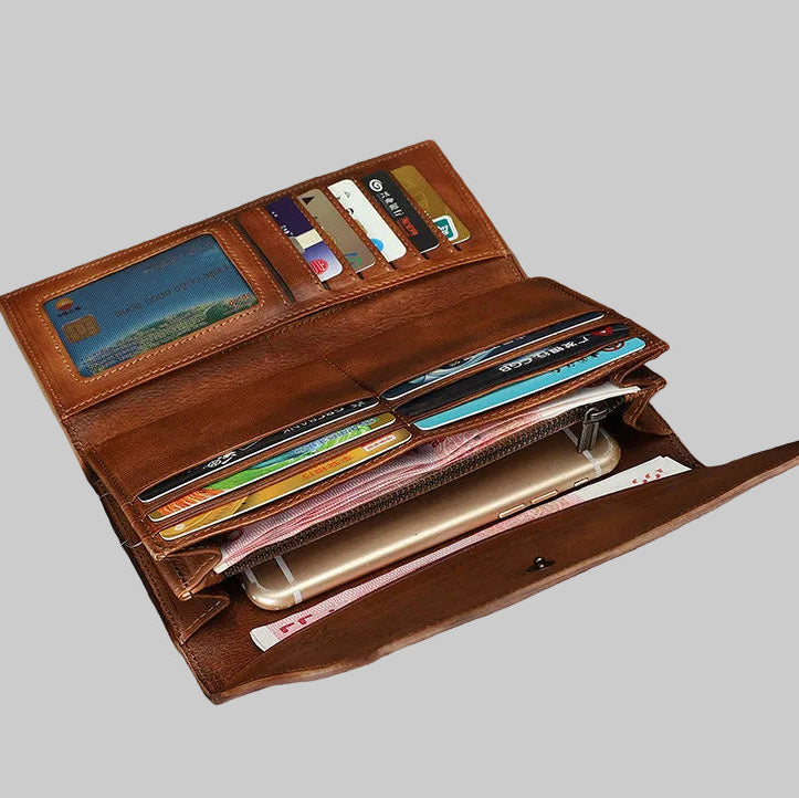 Brown leather wallet with various cards and a phone on a wooden surface