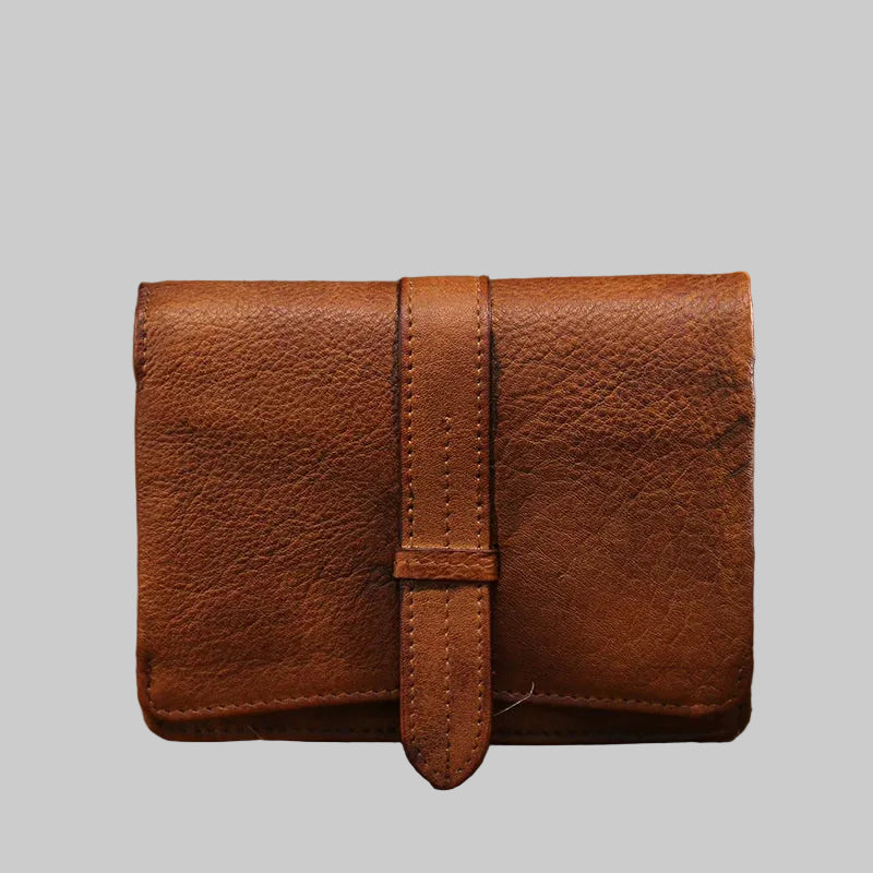 Brown leather pouch on a wooden surface with a blurred natural background