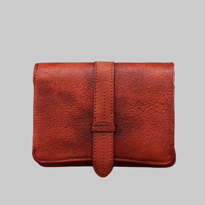 Red leather wallet on a textured surface with a blurred natural background