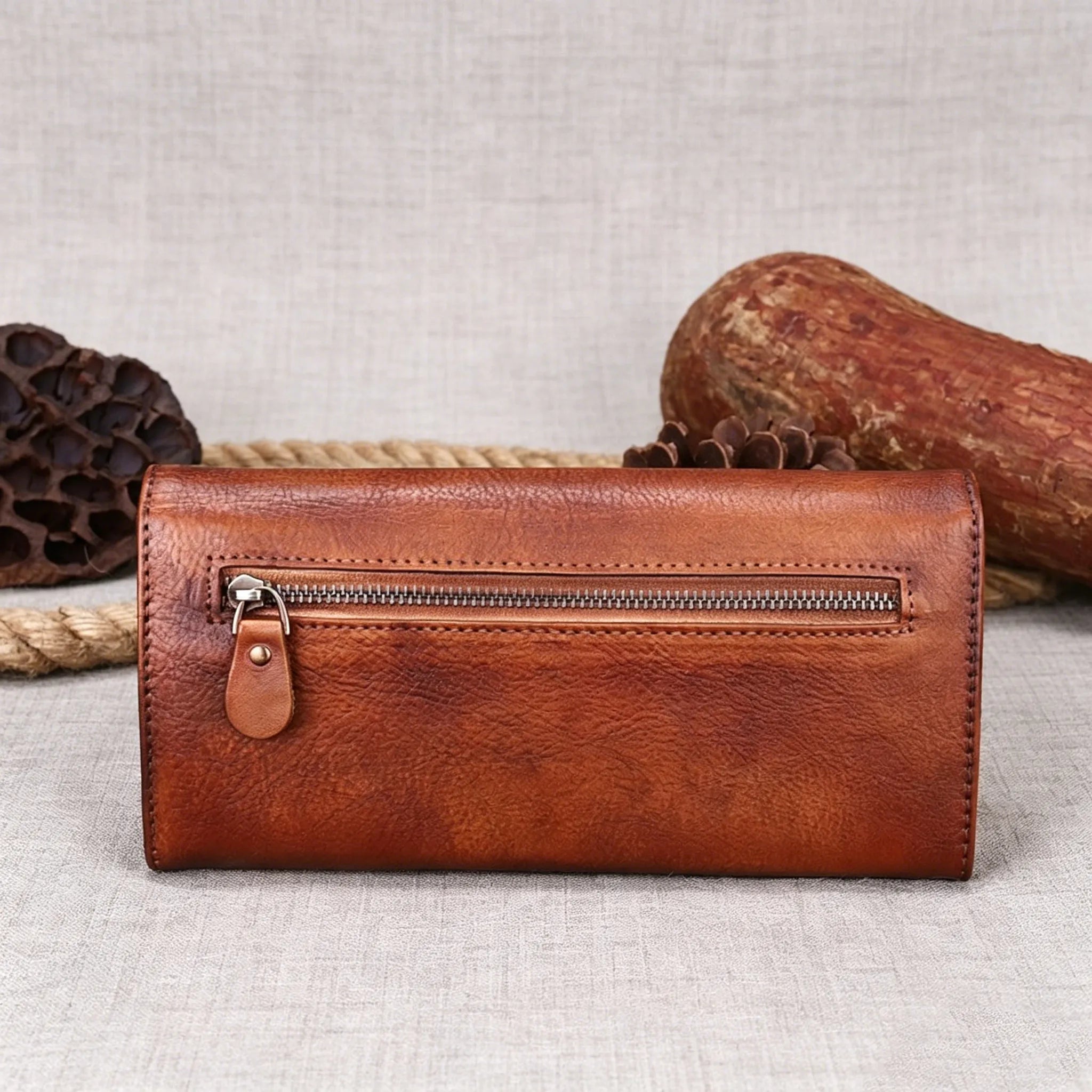 Brown leather wallet with a zipper on a textured surface
