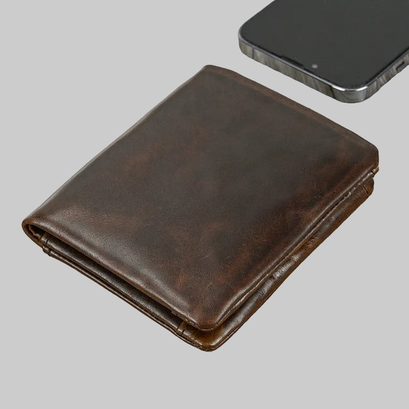 Brown leather wallet next to a smartphone on a gray background