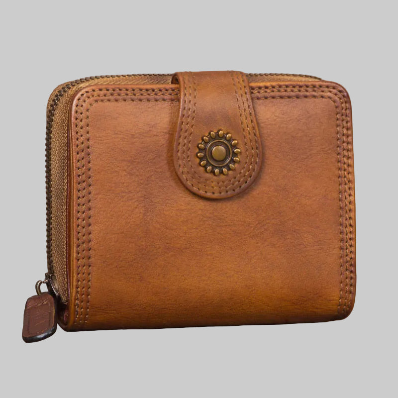 Brown leather wallet with decorative clasp on a wooden surface