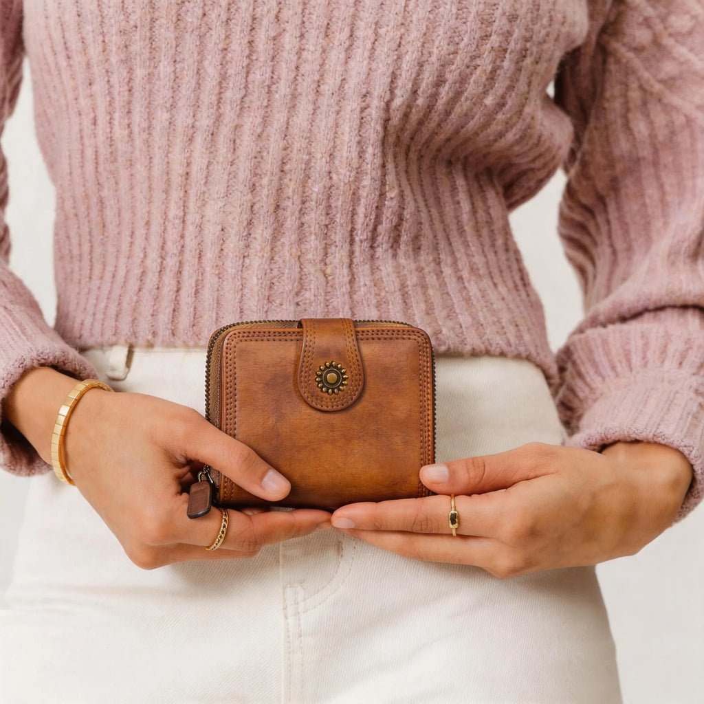 Person holding a brown leather wallet with a neutral background