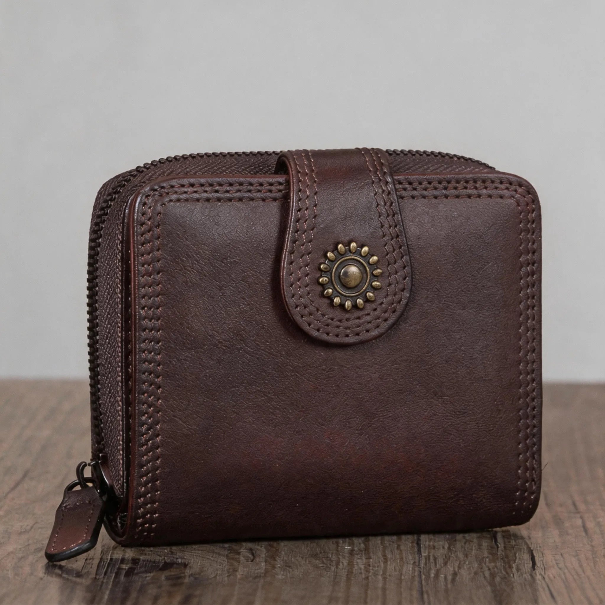 Brown leather wallet with decorative button on a wooden surface