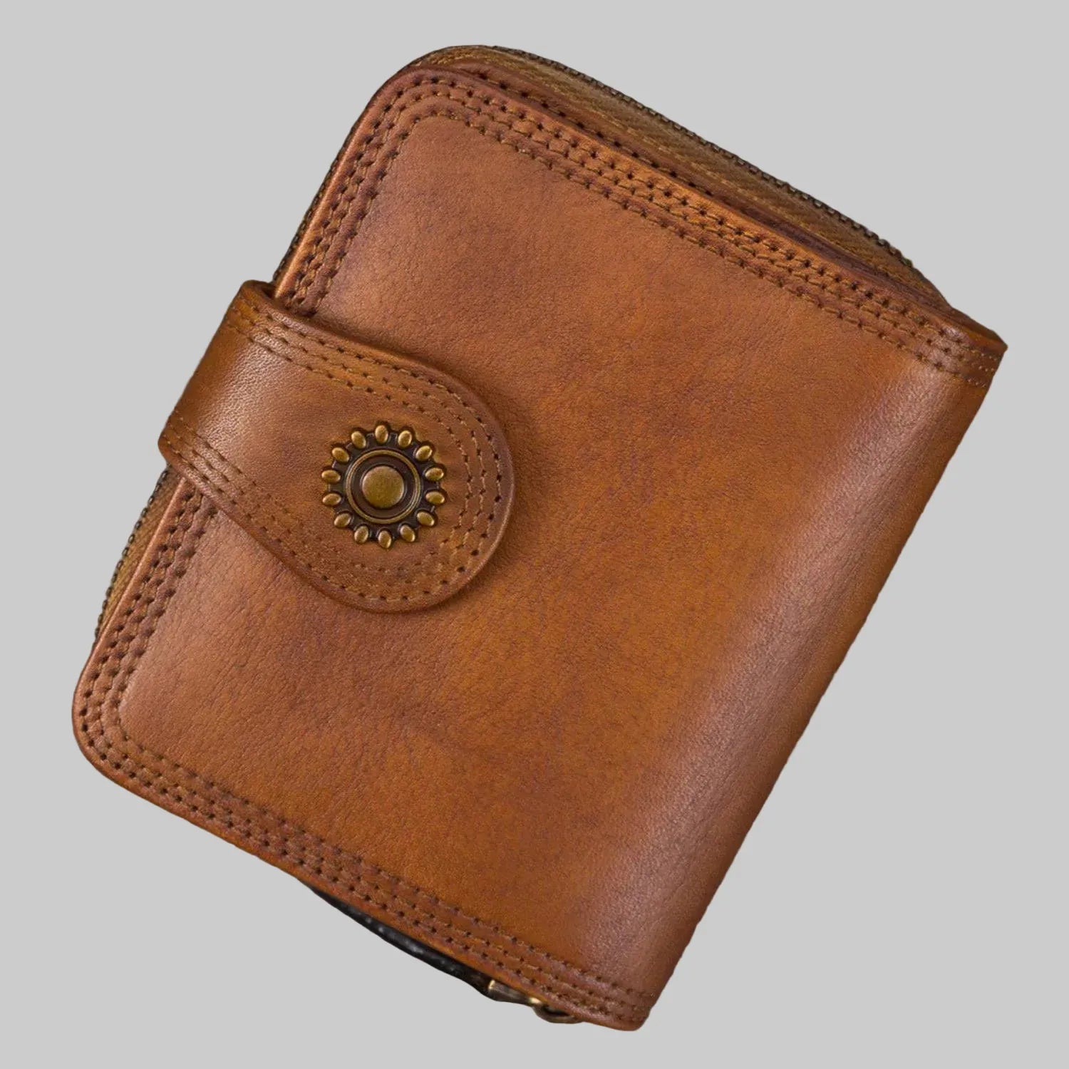 Brown leather wallet with decorative clasp on a gray background