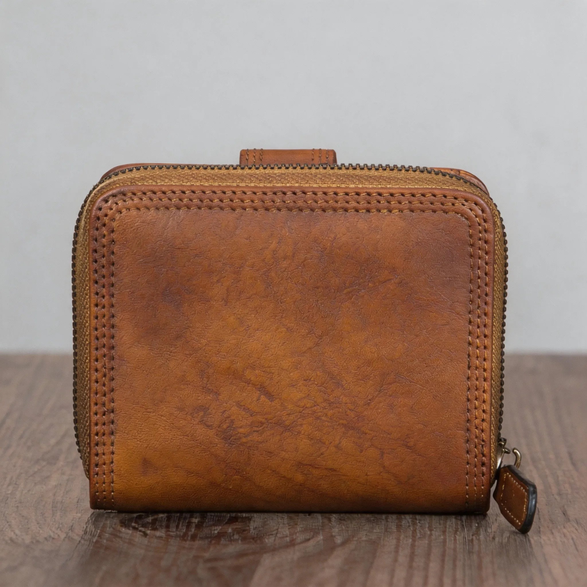 Brown leather wallet on a wooden surface with a gray background