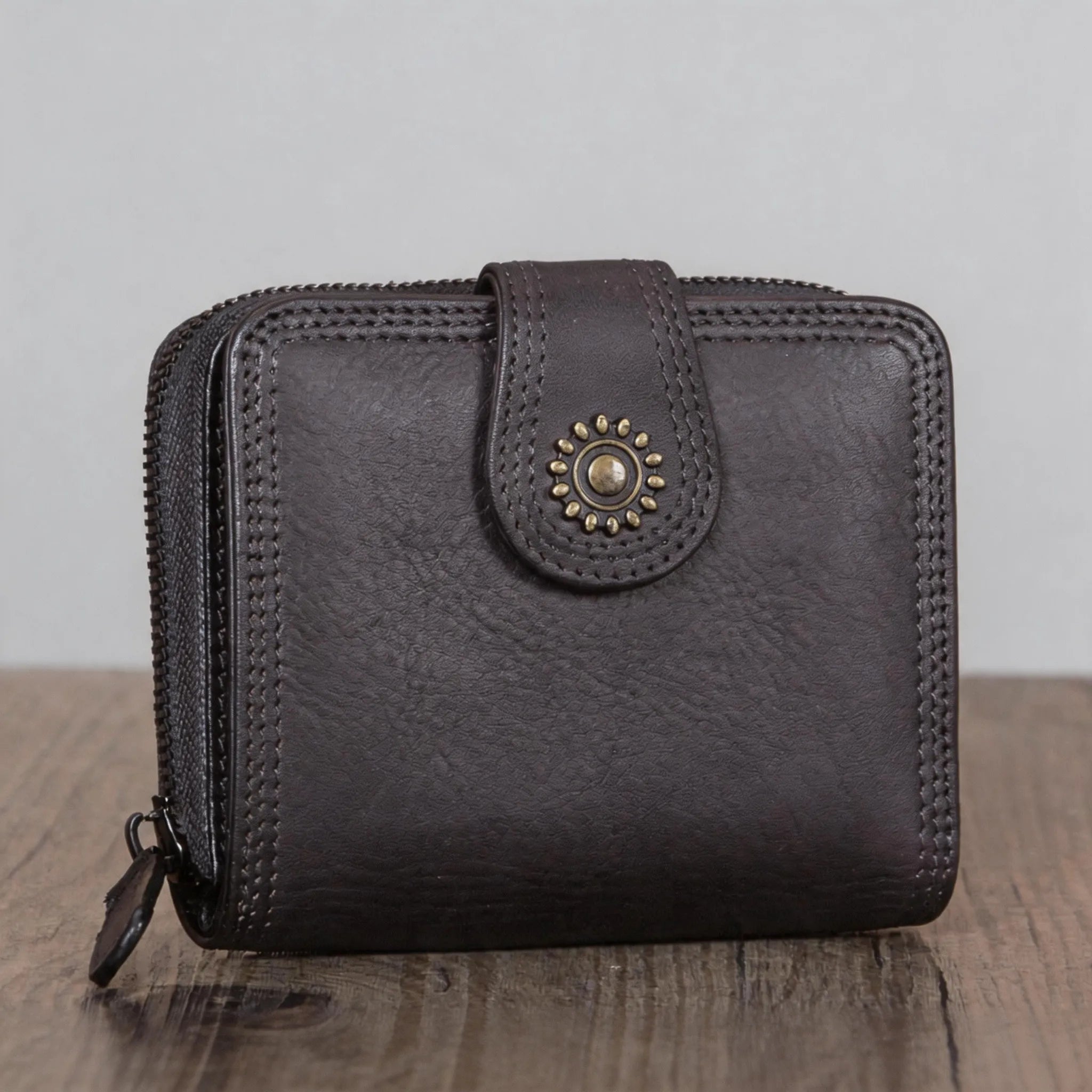 Black leather wallet with decorative clasp on a wooden surface