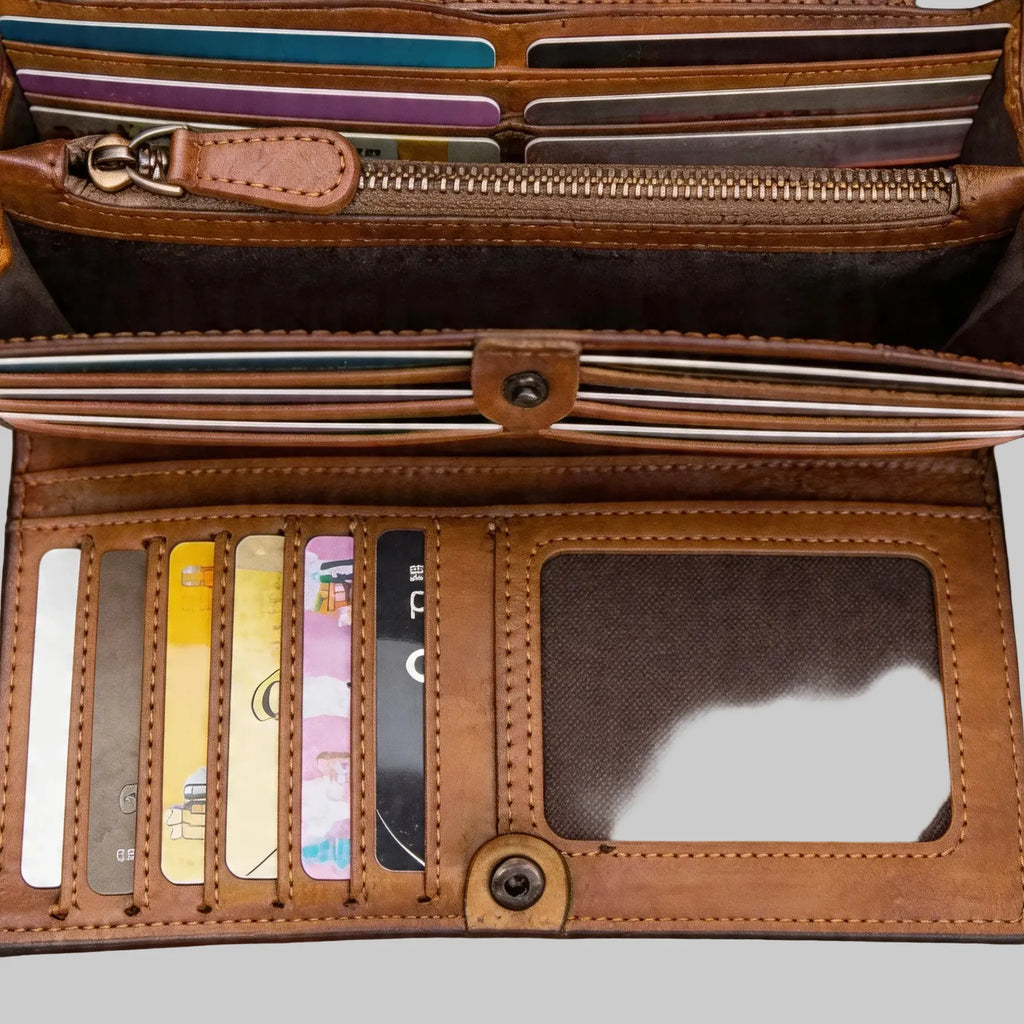 Open brown leather wallet with card slots on a wooden surface