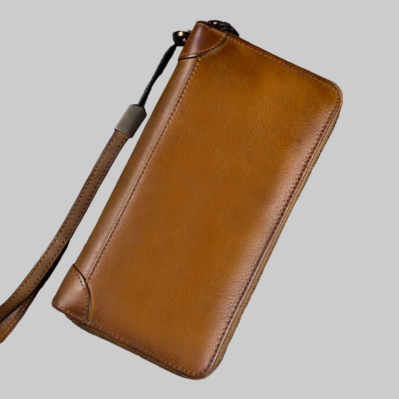 Brown leather wallet with strap on a wooden surface