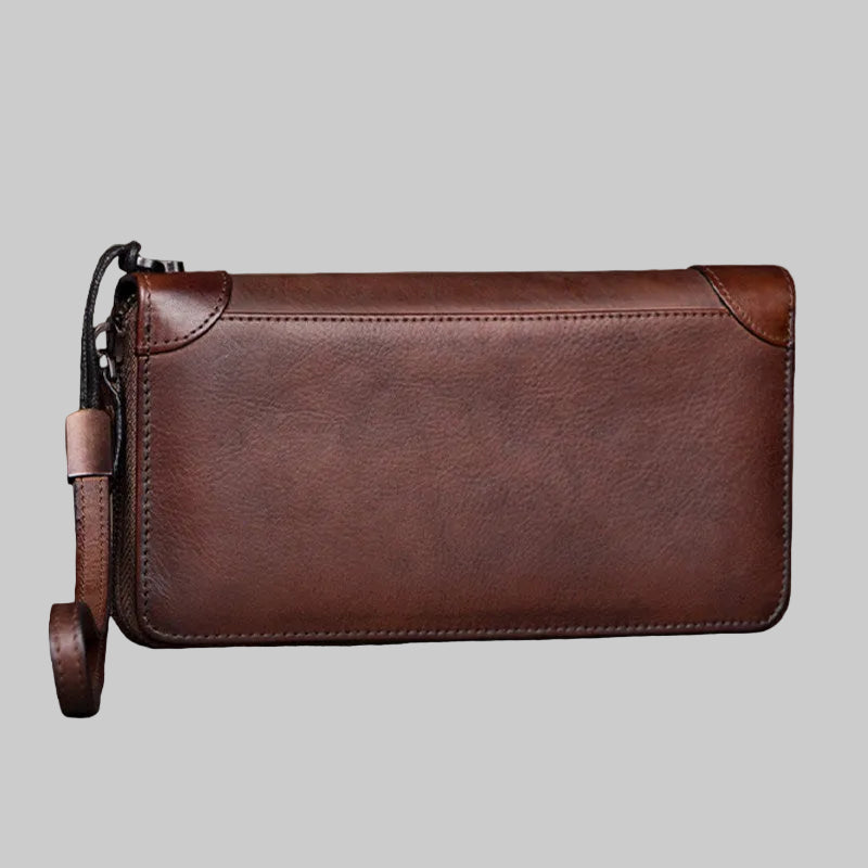 Brown leather clutch bag on a wooden surface with a blurred background