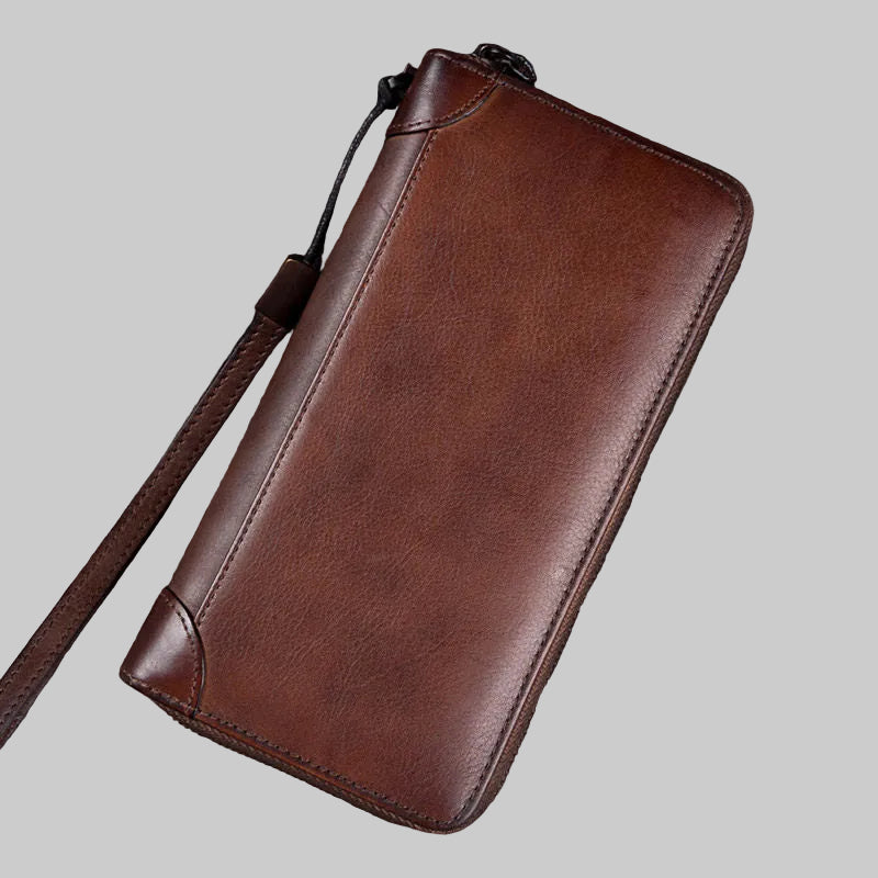 Brown leather wallet with strap on a wooden surface