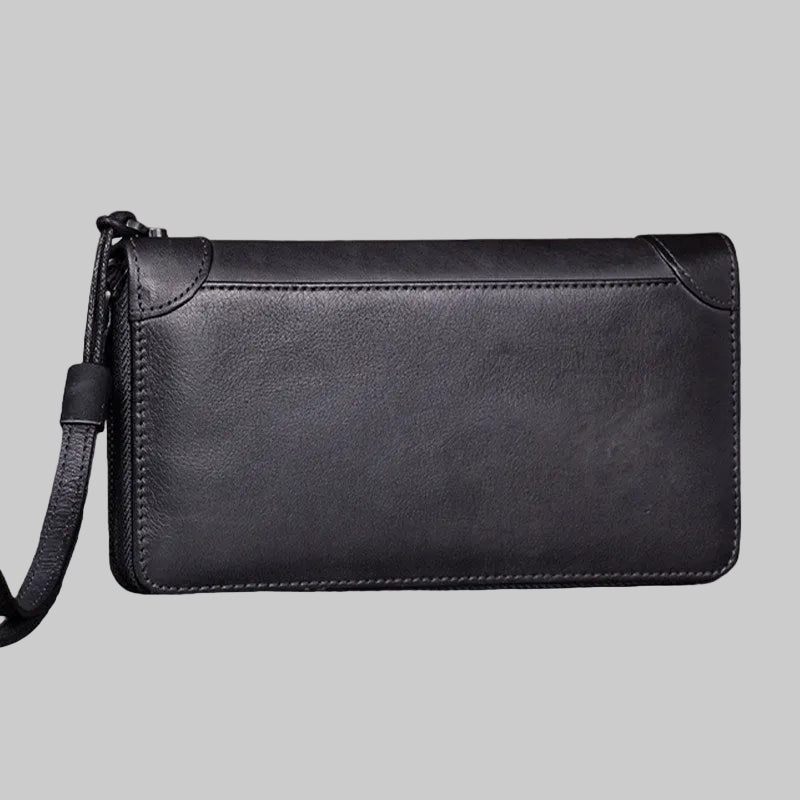 Black leather clutch bag on a wooden surface with a blurred background
