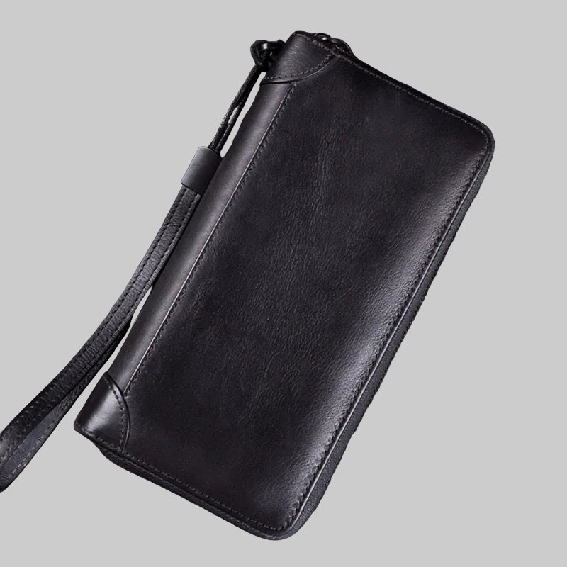 Black leather wallet with strap on a wooden surface