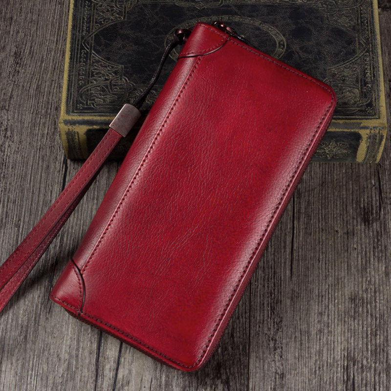 Red leather wallet with strap on a wooden surface
