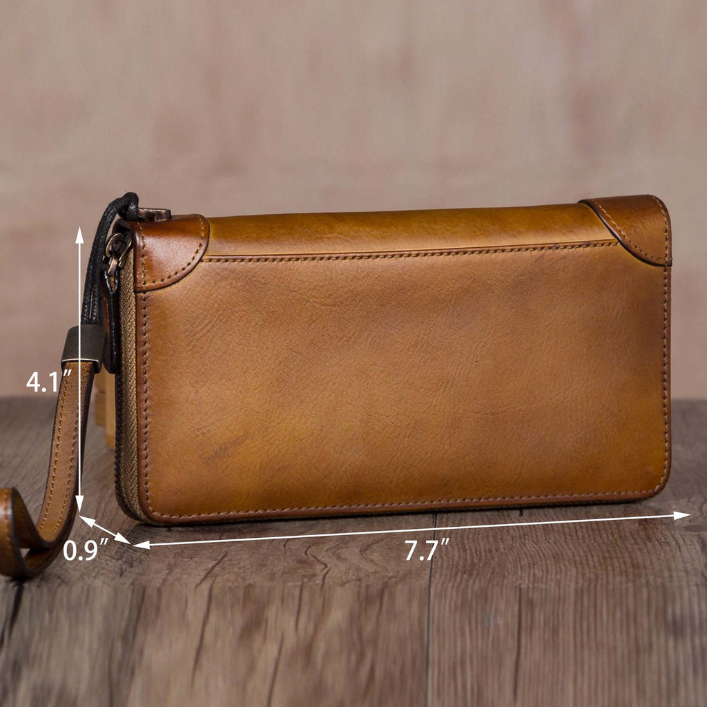 Brown leather clutch bag with measurements on a wooden surface