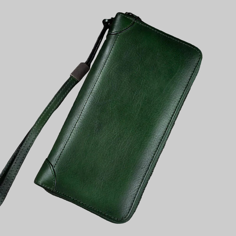 Green leather wallet with strap on a wooden surface