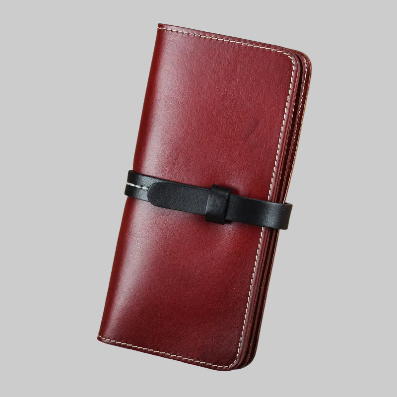 Red leather wallet with a black strap on a brown background