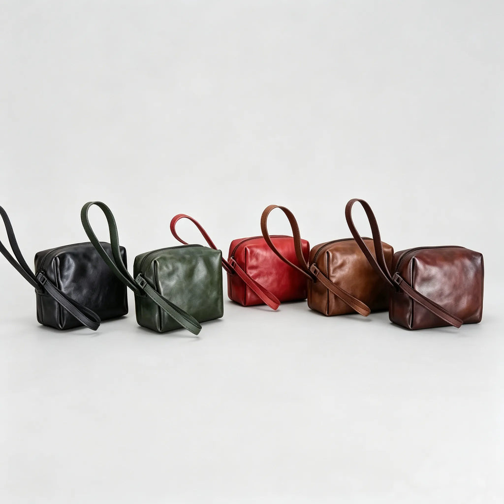 Five leather handbags in black, green, red, brown, and dark brown on a light gray background.