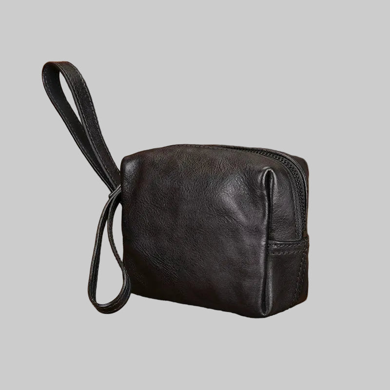 Black leather pouch with a strap on a textured brown surface