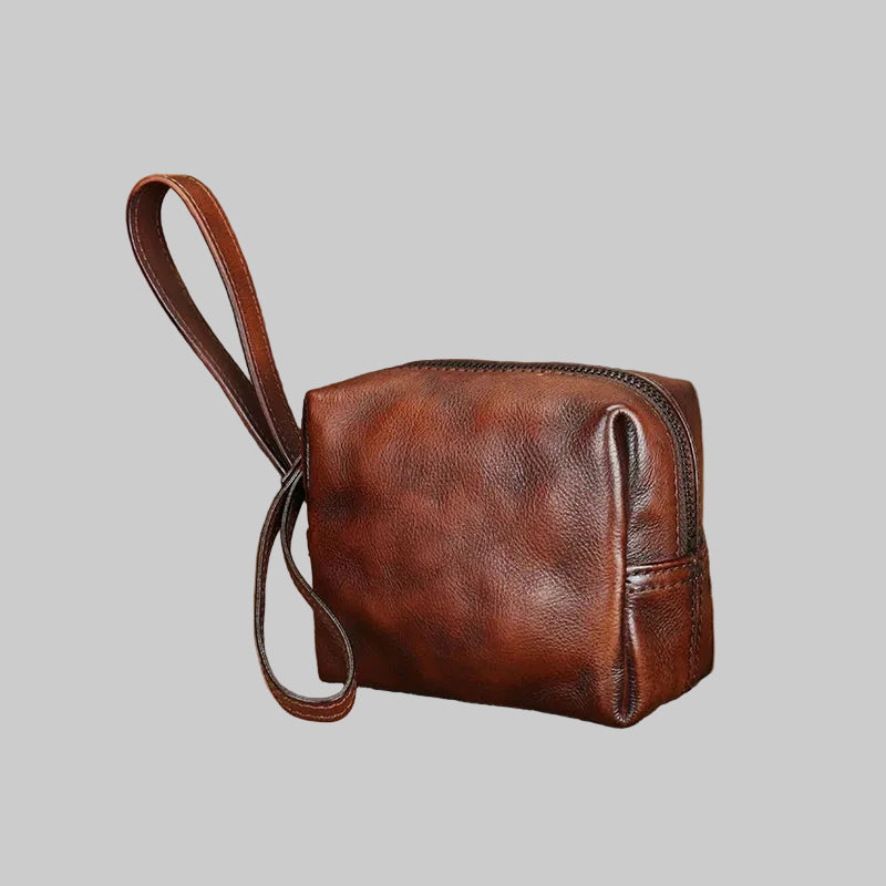 Brown leather pouch with strap on a textured surface
