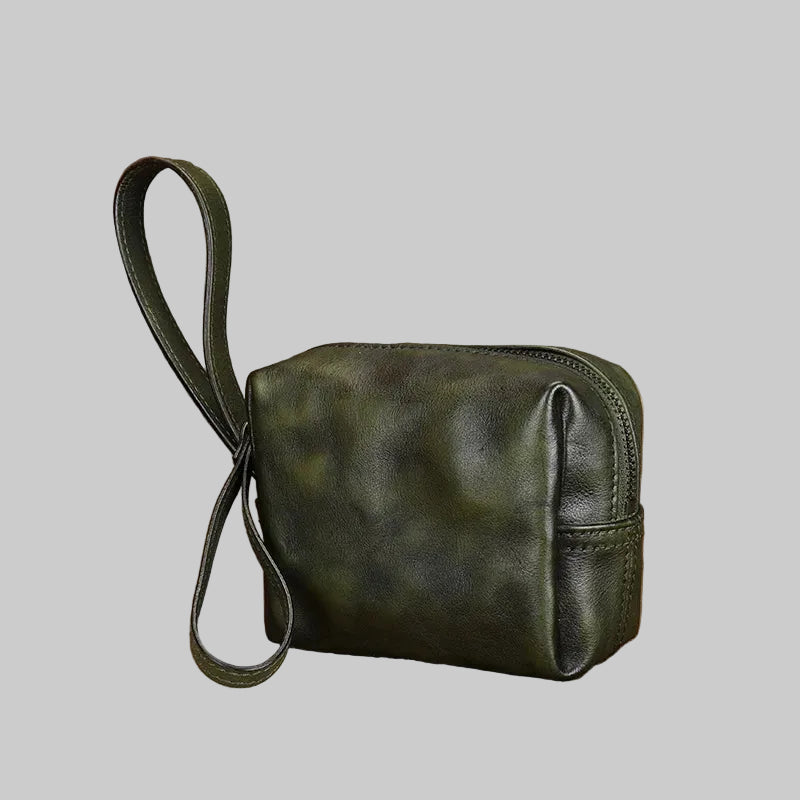 Green leather handbag with a strap on a textured surface