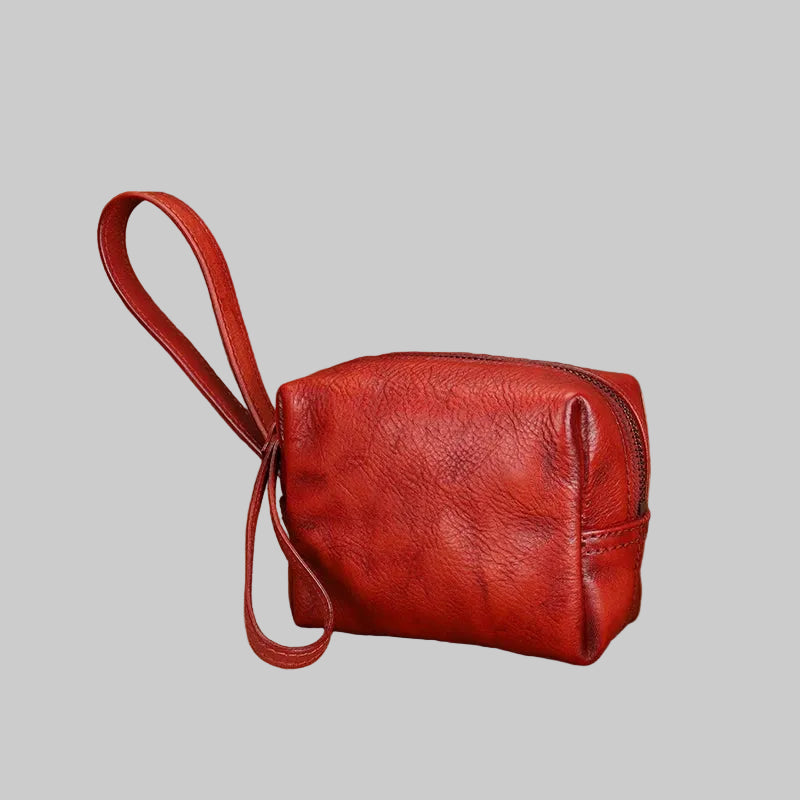 Red leather pouch with strap on a textured surface