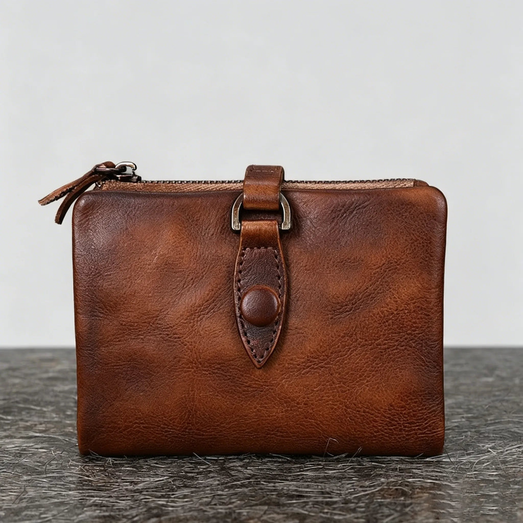 Brown leather wallet with a strap on a gray surface