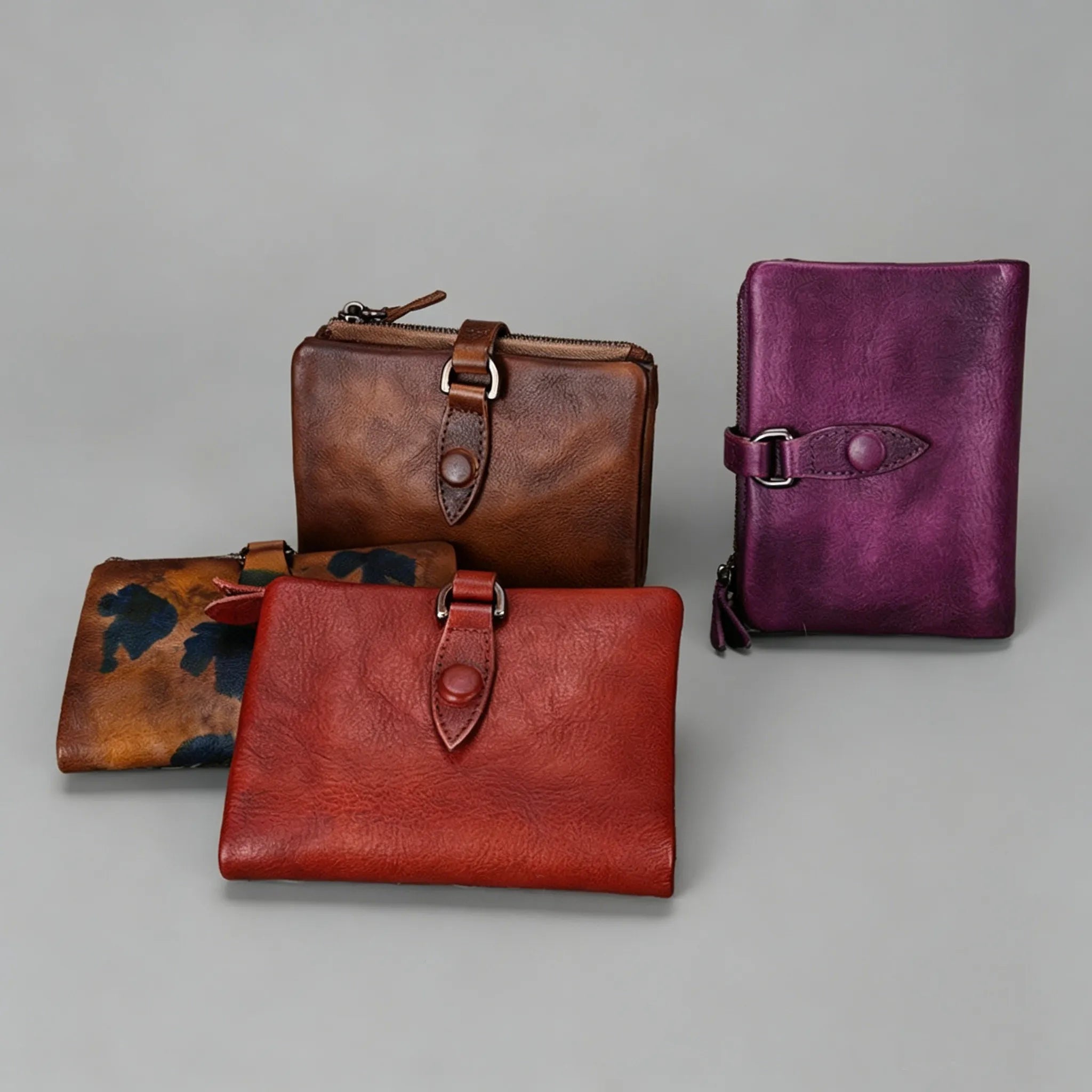Four leather wallets in different colors on a gray background
