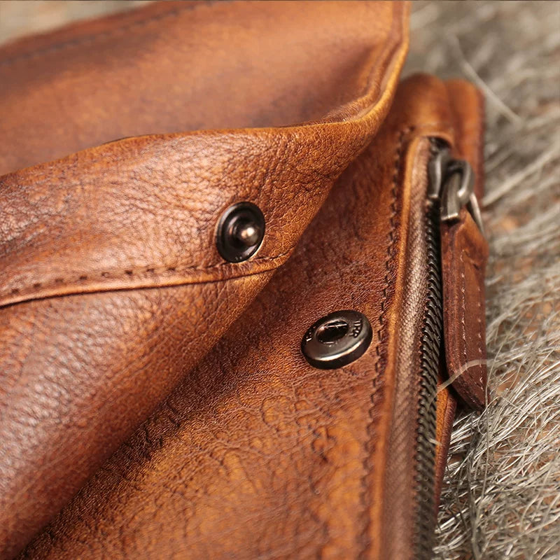Close-up of a brown leather bag with metal zippers and buttons.