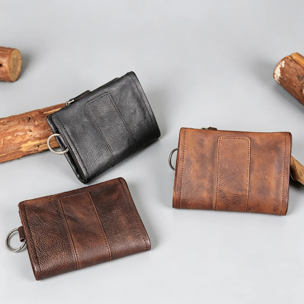 Three leather wallets in black and brown on a light gray background with wooden sticks.